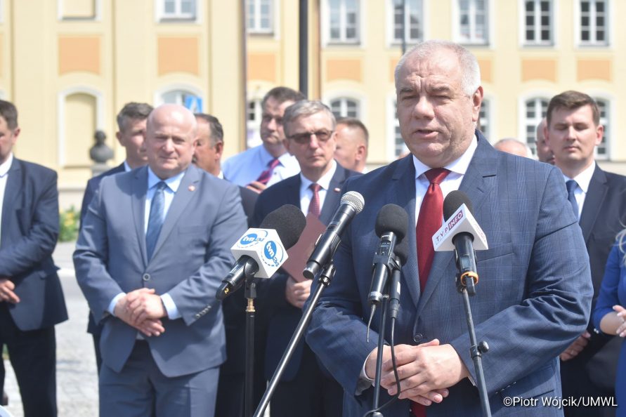 Podpisanie umowy na reitalizację Zespołu Pałacowego Potockich w Radzyniu Podlaskim. Przy mikrofonach stoi Minister Aktywów Państwowych, Wicepremier Jacek Sasin. W tle grupa ludzi, wśród której (od lewej) stoi Marszałek Województwa Lubelskiego Jarosław Stawiarski