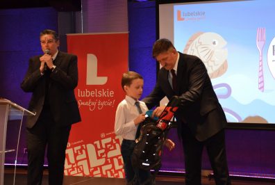 Członek Zarządu Województwa Lubelskiego, Pan Zdzisław Szwed, wręczający nagrodę laureatowi konkursu „Ryba na talerzu” - czarny plecak z pozostałymi nagrodami w środku.