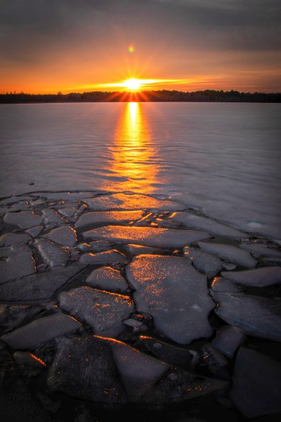 Na infografice umieszczone jest zwycięskie zdjęcie, które pokazuje zachód słońca nad jeziorem częściowo skutym lodem.