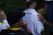 Kolarz podpisuje swoim autografem koszulkę dla dziewczynki