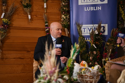 Marszałek Jarosław Stawiarski w trakcie wywiadu w otoczeniu palm wielkanocnych