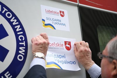 Wicemarszałek wiesza na karetce kartkę z napisem: Solidarni z Ukrainą