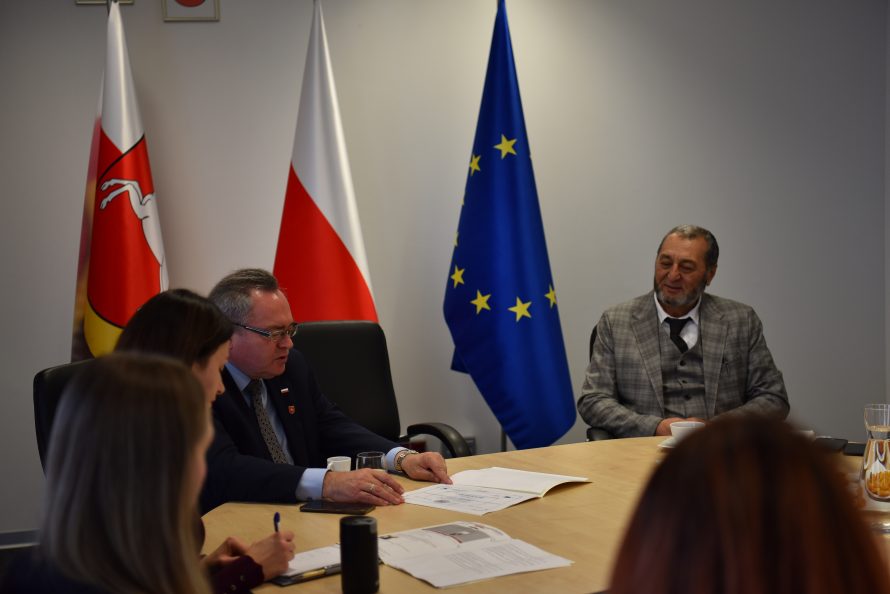 wicemarszałek Zbigniew Wojciechowski i przedstawiciel Tadżykistanu siedzą wspólnie przy stole, za nimi znadjują się flagi polska i UE