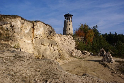Wysoka skała z ustawionym na niej wieżą to zdjęcie fragmentu szlaku geoturystycznego Roztocza Środkowego przedstawiające kamieniołom w Józefowie