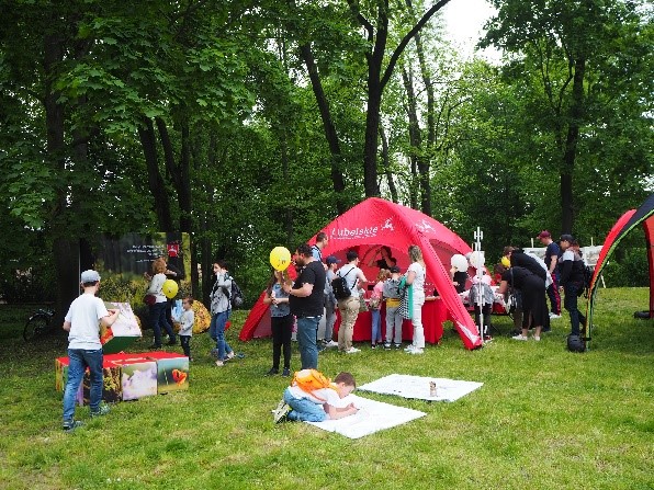 Polana i rozłożony namiot promocyjny i uczestnicy pikniku rodzinnego