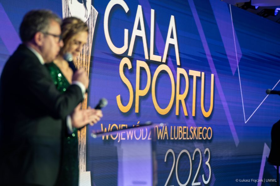 Dwóch konferansjerów podczas prowadzenia gali oraz wielki ekran z napisem Gala Sportu