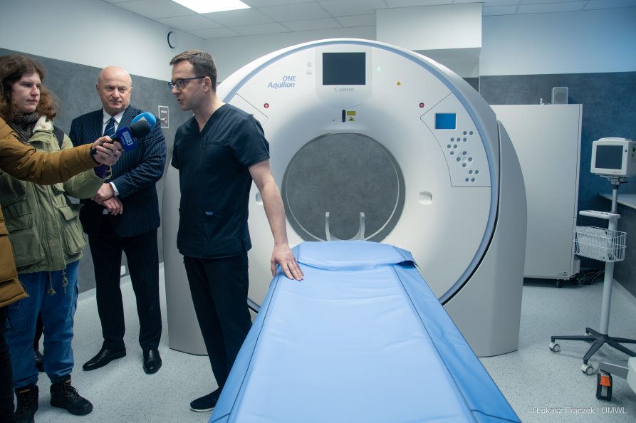 Lekarz prezentuje aparato do tomografu, obok niego stoją marszałek WL oraz dziennikarze