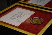 Medal wraz z dyplomem oprawiony w szklaną ramkę leży na stole
