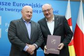 Marszałek Jarosław Stawiarski w towarzystwie burmistrza Urzędowa, przekazuje mu dofinansowanie z Funduszy europejskich na sektor edukacji