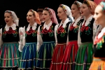 Około dziesięciu młodych kobiet ubranych w stroje ludowe. Stoją obok siebie w trakcie śpiewaczego występu