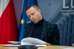Na zdjęciu widoczny jest mężczyzna- Michał Mulawa, Wicemarszałek Województwa Lubelskiego, który siedzi przy stoliku. W tle znajdują się dwie flagi- Polski oraz Unii Europejskiej.