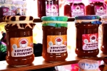 Zdjęcie przedstawia produkty regionalne – miody. Miody stoją na półkach w słoiczkach z etykietkami i kolorową tkaniną okrywającą wieczka