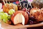 Zdjęcie przedstawia produkty regionalne – sery. Sery w panierce ułożone są na drewnianym półmisku obok winogron i innych owoców
