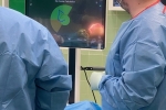 Dwóch lekarzy stoi tyłem do fotografa, przyglądaja się obrazowi jaki pokazuje się na monitorze USG