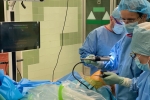 Trzech lekarzy chirugów stoi przy stole operacyjnym nad pacjentem, w trakcie wykonywania zabiegu