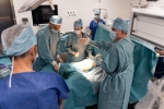 Kilku lekarzy chirurgów stoi przy stole chirurgicznym podczas zabiegu na pacjencie