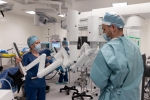 Dwóch lekarzy chirurgów w fartuchach stoi na sali operacyjnej przy robocie