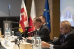 Przewodniczący i dwóch wiceprzewodniczących Sejmiku Województwa Lubelskiego siedzą przy stołach zwróceni twarzami do Radnych