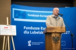 Jarosław Stawiarski Marszałek Województwa Lubelskiego stoi przy mównicy za nim znajduje się ścianka z napisem Fundusze Europejskie dla Lubelskiego 2021-2027