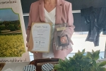 kobieta na stoisku promocyjnym trzymająca nagrodę Perła 2023 i dyplom