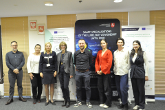 Uczestnicy spotkania ustawieni do wspólnego zdjęcia. Grupa liczy osiem osób w ubraniach charakterystycznych dla stylu smart casual. Za uczestnikami ustawione są trzy ścianki: dwie należące do projektu ACTT4 Cosmetics oraz jedna z napisem "Smart specialisations of the Lubelskie Voivodeship until 2030".