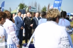 pomiędzy przechodzącymi ludźmi widać w tle marszałka województwa lubelskiego, członka zarządu oraz inni witający korowód dożynkowy.