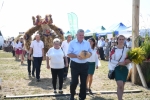 zbliżenie na korowód , w ciągu widać ludzi niosących różne wieńce dożynkowe.