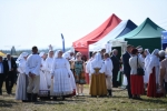 Widok na grupę ludzi w strojach ludowych. Z tyłu widać namioty.