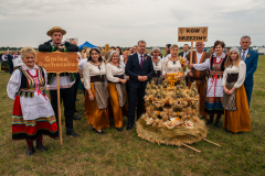 Koło Gospodyń Wiejskich z Brzezin pozuje do zdjęcia wraz ze swoim wieńcem przypominającym bogato zdobioną koronę. 