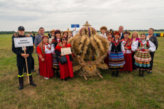 Koło Gospodyń Wiejskich z powiatu włodawskiego pozuje do zdjęcia wraz ze swoim wieńcem przypominającym królewską koronę.