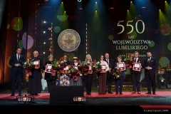 Przedstawicie instytucji które otrzymały medal 550- lecia stoją na scenie i pozują do  wspólnego zdjęcia wraz z członkami zarządu województwa lubelskiego