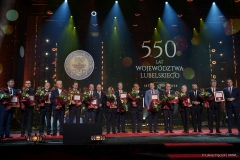 Przedstawiciele  instytucji, które otrzymały medal 550-lecia stoją wspólnie na scenie i pozują do zdjęcia wraz z członkami zarządu województwa lubelskiego