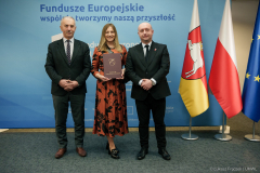 Marszałek Jarosław Stawiarski i wicemarszałek Piotr Breś na wspólnym zdjęciu z beneficjentką dofinansowania