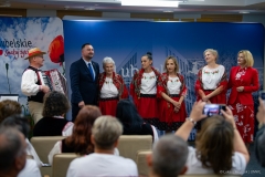 Wicemarszałek Marek Wojciechowski w towarzystwie Pań z koła gospodyń wiejskich. Wspólnie stoją w małej sali konferencyjnej i śpiewają