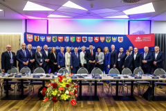 Na zdjęciu widoczna jest grupa ludzi (kobiety i mężczyźni), którzy ustawienisą w jednym rzędzie. Stoją oni na tle ścianki z napisem „Konwent Marszałków Województw RP, Małopolska 2025”.  Są to Marszałkowie Polskich Województw, którzy uczestniczyli w II Posiedzeniu Konwentu Marszałków w Woj. Małopolskim. Wśród nich jest Jarosław Kwasek, Członek Zarządu Województwa Lubelskiego. Przed grupą ludzi widoczne są ławki z krzesłami, a przed nimi centralnie na złotym stojaku znajduje  bukiet czerwonych i żółtych kwiatów.