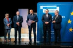 Na scenie stoi czterech mężczyzn i jedna kobieta. Mężczyzna stojący w środku to Prezydent Miasta Lublin, który otrzymał dokument dofinansowania i przy tej okazji przemawia do zebranych