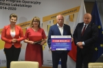 Przekazanie czeków na realizację działań związanych z przeciwdziałaniem skutkom rozprzestrzeniania się pandemii Covid-19 w domach pomocy społecznej. Od lewej: zastępca dyrektora ROPS Marta Drozd, Członek Zarządu Powiatu Chełmskiego Grażyna Szykuła, Starosta Chełmski Piotr Deniszczuk trzyma czek z wypisaną kwotą dofinansowania, Marszałek Jarosław Stawiarski