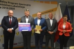 Przekazanie czeków na realizację działań związanych z przeciwdziałaniem skutkom rozprzestrzeniania się pandemii Covid-19 w domach pomocy społecznej. Od lewej Marszałek Jarosław Stawiarski, Starosta Krasnostawski Andrzej Leńczuk trzyma czek z wypisaną kwotą dofinansowania, Wicestarosta Marek Nowosadzki trzyma teczkę z umową dofinansowania, Skarbnik Powiatu Janusz Cięciera, zastępca dyrektora ROPS Marta Drozd