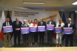 Przekazanie czeków na realizację działań związanych z przeciwdziałaniem skutkom rozprzestrzeniania się pandemii Covid-19 w domach pomocy społecznej. Od lewej: Andrzej Szarlip starosta biłgorajski, Marszałek Jarosław Stawiarski, Andrzej Rolla Starosta Kraśnicki, Małgorzata Malczuk dyrektor PCPR w Białej Podlaskiej, zastępca dyrektora ROPS w Lublinie Marta Drozd, Stanisław Grześko starosta zamojskim, Andrzej Leńczuk starosta krasnowstawski, Katarzyna Fus dyrektor MOPR w Lublinie, Piotr Deniszczuk starosta chełmski. Wszyscy starostowie oraz panie dyrektor trzymają czeki z wypisanymi kwotami dofinansowania.