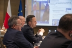 Członkowie Zarządu siedzą przy stołach podczas sesji, za nimi w tle widoczny jest duży ekran wyświetlający radnego