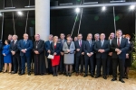 Widok na uczestników spoktania opłatkowego. Około dwudziestu osób stoi w dwurzędzie w pomieszczeniu. Wśród zebranych na pierwszym planie stoją członkowie zarządu województwa lubelskiego