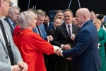 Marszałek Jarosław Stawiarski podaje opłatek zebranym, dokooła niego znajduje się kilkanaście osób
