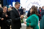 Członek Zarzadu Zdzisław Szwed dzieli się opłatkiem z kobietą, w tle pozostali uczestnicy spotkania składający sobie życzenia