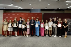 Członek Zarządu WL Marcin Szewczak pozuje do wspólnego zdjęcia ze stypendystami. Wszyscy stoją w sali konferencyjnej za nimi znajduje się ścianka lubelskie smakuj życie i 550 lecie województwa lubelskiego