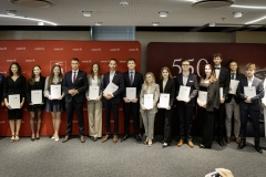 Członek Zarządu WL Marcin Szewczak pozuje do wspólnego zdjęcia ze stypendystami. Wszyscy stoją w sali konferencyjnej za nimi znajduje się ścianka lubelskie smakuj życie i 550 lecie województwa lubelskiego