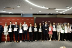 Członek Zarządu WL Marcin Szewczak pozuje do wspólnego zdjęcia ze stypendystami. Wszyscy stoją w sali konferencyjnej za nimi znajduje się ścianka lubelskie smakuj życie i 550 lecie województwa lubelskiego
