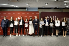 Członek Zarządu WL Marcin Szewczak pozuje do wspólnego zdjęcia ze stypendystami. Wszyscy stoją w sali konferencyjnej za nimi znajduje się ścianka lubelskie smakuj życie i 550 lecie województwa lubelskiego