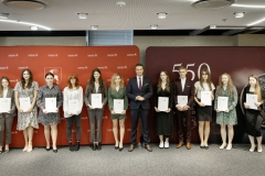 Członek Zarządu WL Marcin Szewczak pozuje do wspólnego zdjęcia ze stypendystami. Wszyscy stoją w sali konferencyjnej za nimi znajduje się ścianka lubelskie smakuj życie i 550 lecie województwa lubelskiego