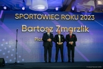 Siedem osób stoi na scenie i pozuje do zdjęć, trzymają w rękach dyplomy i kwiaty