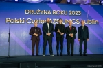 Mężczyzna trzyma w rękach dyplom i kwiaty obok niego stoją trzy kobiety i jeden mężczyzna